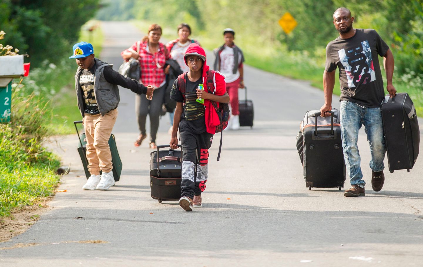 A group of people who claim to be from Haiti walk down the road in Champlain, New York as they prepare to cross the border into Canada illegally on August 4, 2017.