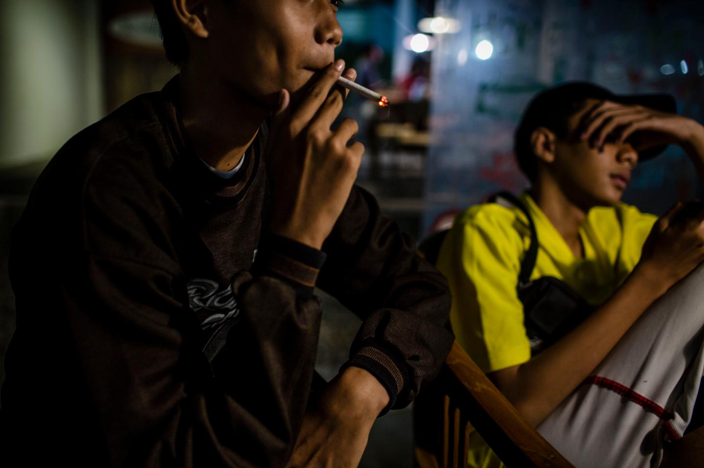 A boy smokes at a coffee shop at night with his friends on March 7, 2017 in Yogyakarta, Indonesia.