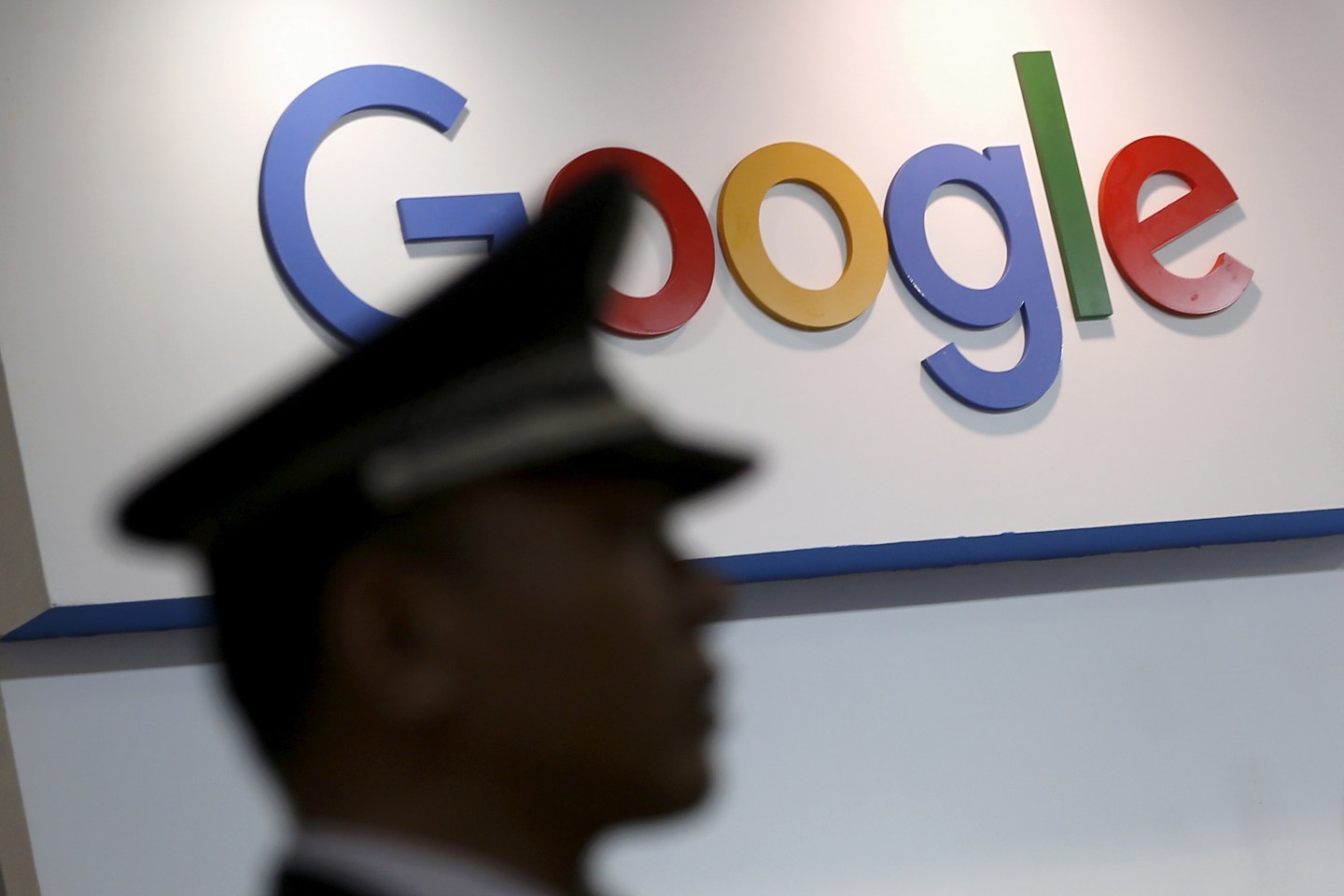 A security guard keeps watch as he walks past a logo of Google in Shanghai