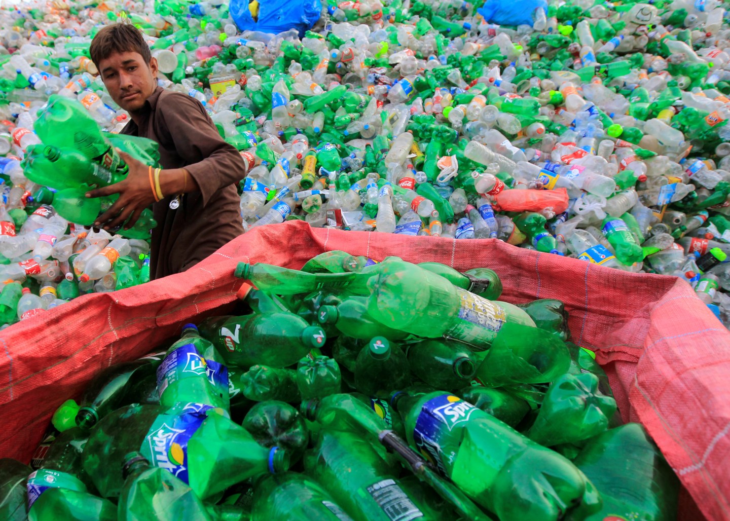 A worker sorts bottles to throw them in a plastic bottle chipper at a recycling workshop in Islamabad