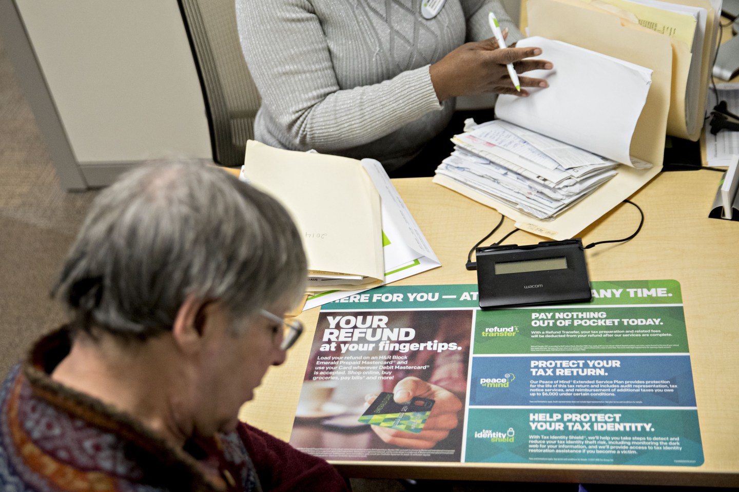 A senior tax analyst, top, speaks with a customer at an H&R Block Inc. tax service office in Washington, D.C, U.S., on Friday, Dec. 29, 2017.