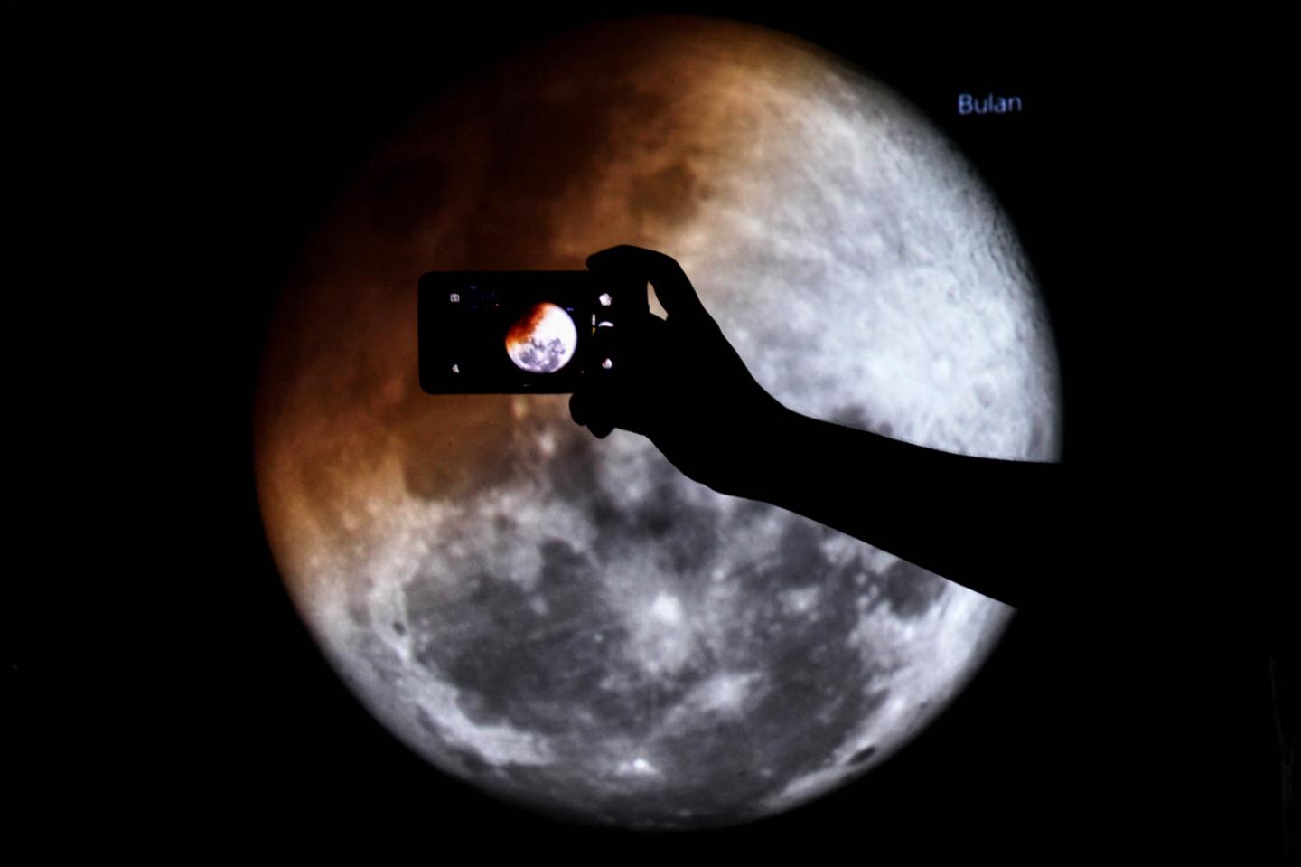 Mobile phone held up against the moon
