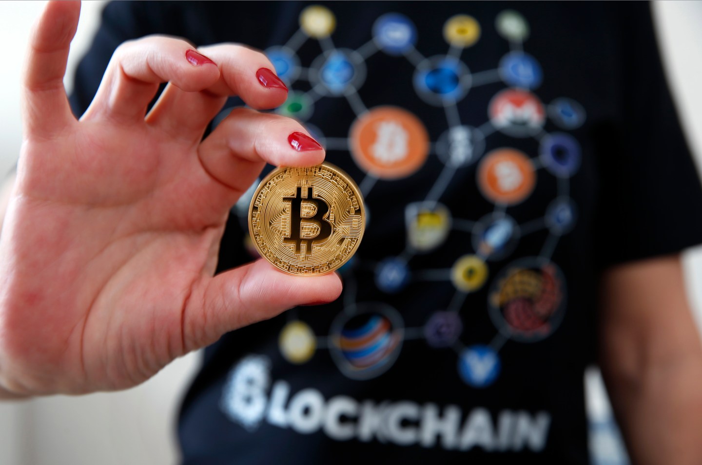 A woman dressed in a t-shirt with cryptocurrency logos holds a visual representation of the cryptocurrency Bitcoin on February 01, 2018 in Paris, France.