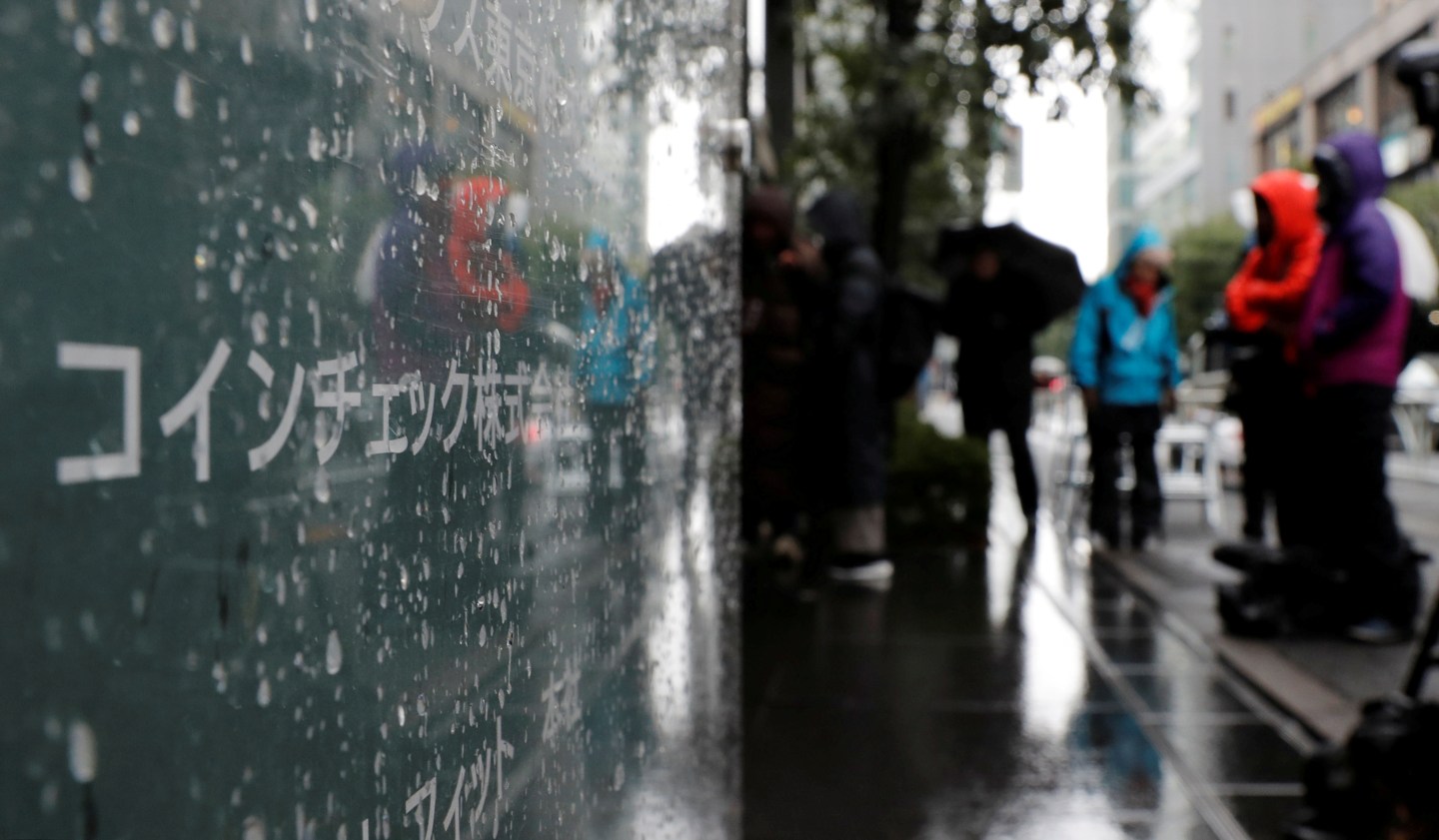 FILE PHOTO: Journalists are seen next to Cryptocurrency exchange Coincheck's signboard while Japan's financial regulator conducts a spot inspection on Coincheck, in Tokyo
