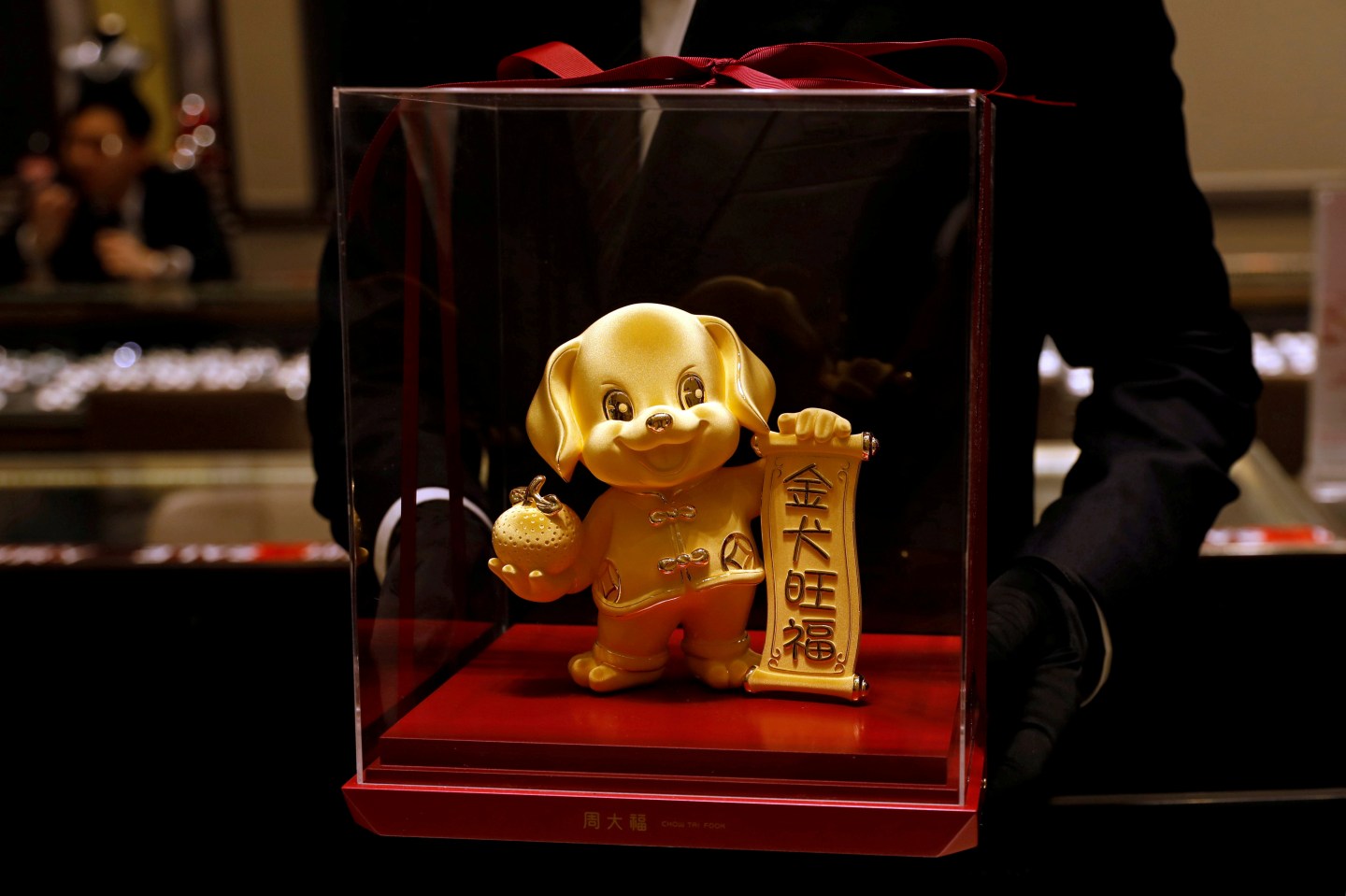 FILE PHOTO: A staff poses with a dog-shaped gold figurine, at Chow Tai Fook Jewellery store ahead of the Lunar Year of the Dog in Hong Kong