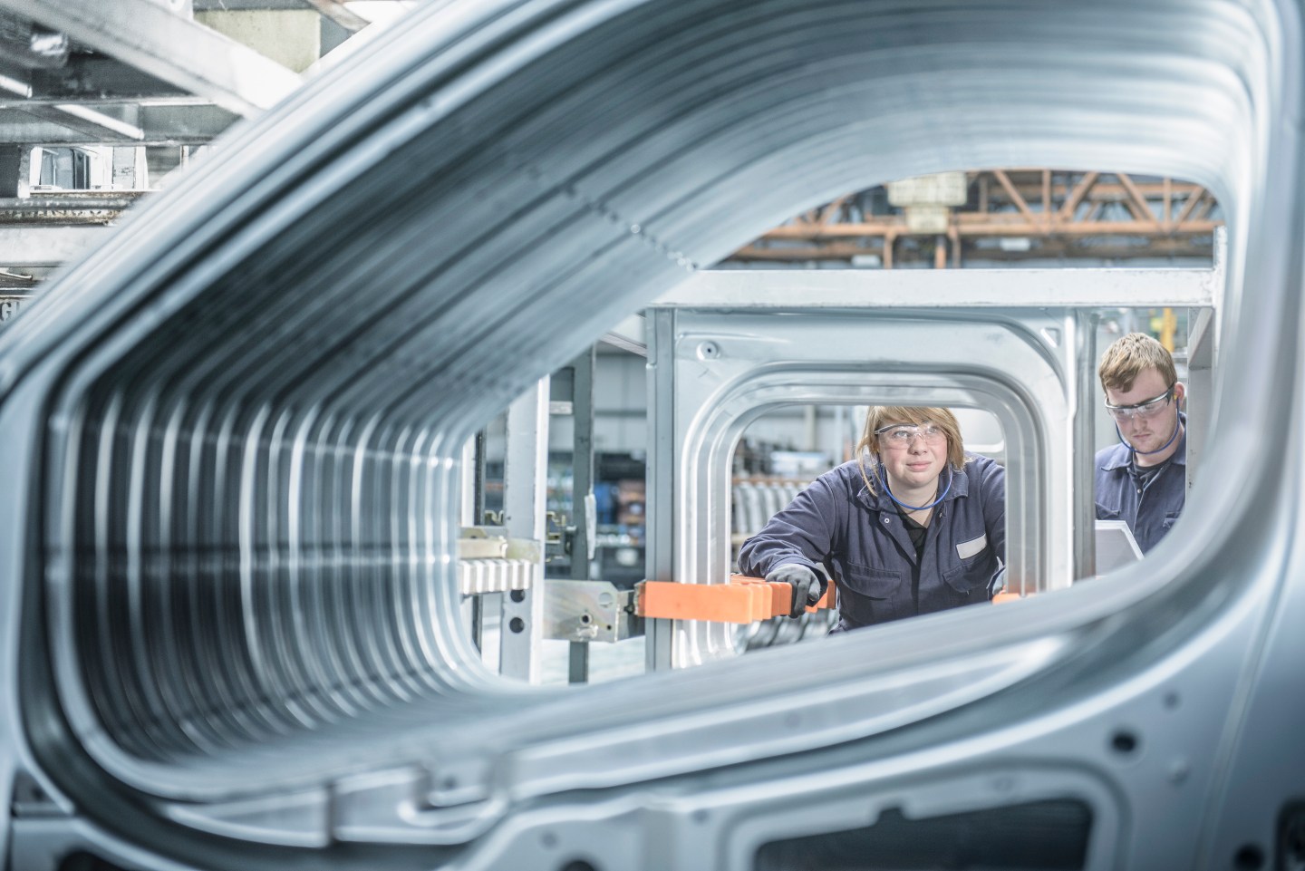 Apprentices inspecting section of car body in car plant