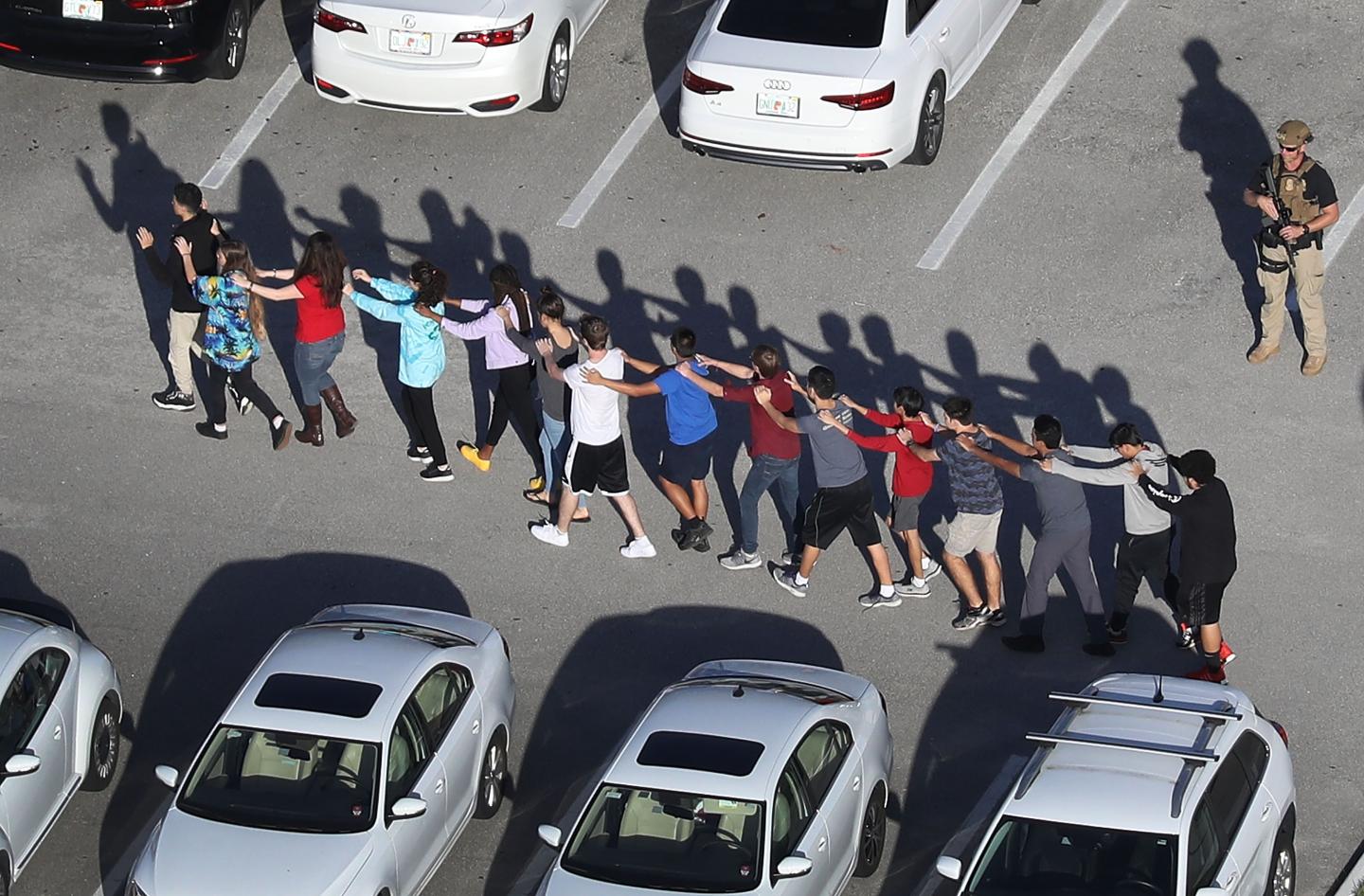 Students walk out of Marjory Stoneman Douglas High School in Parkland Florida after a shooting there. America is now debating arming teachers and gun control.