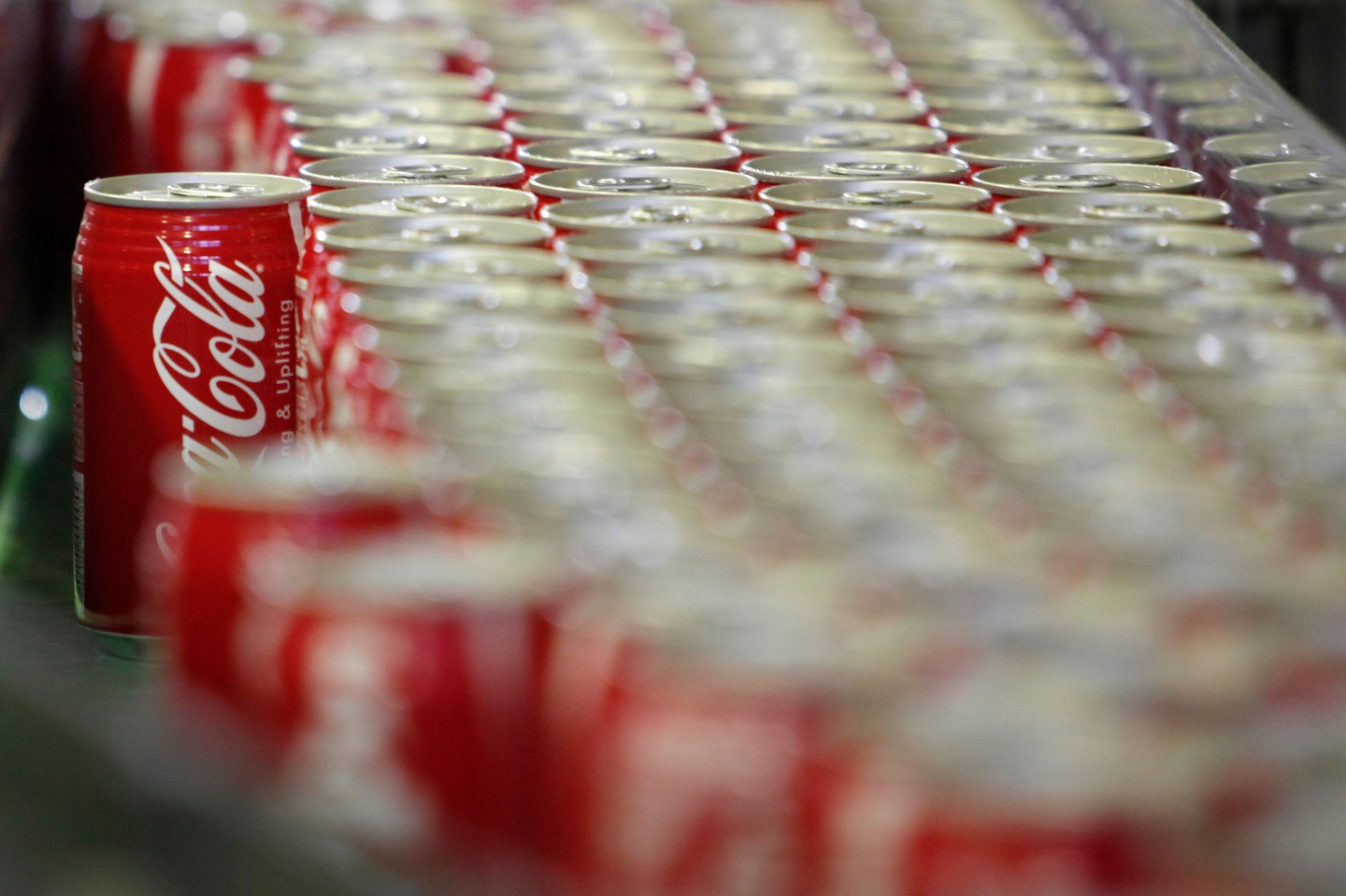 Cans of Coca-Cola roll along an assembly line in a factory