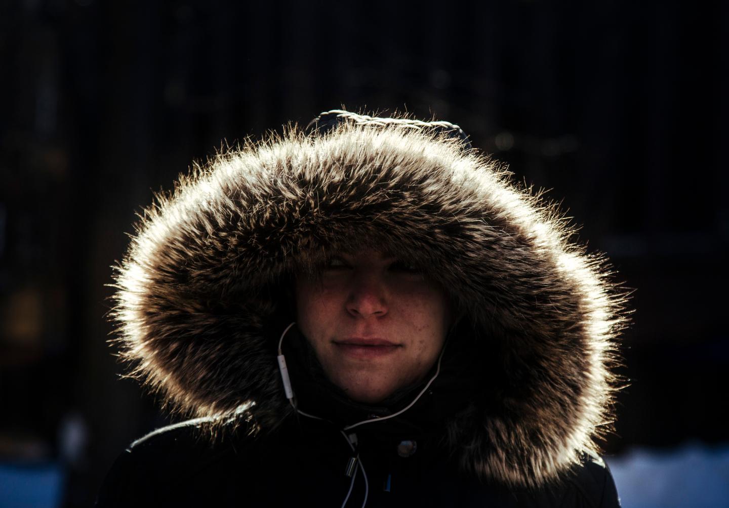 Woman wears hooded coat with fur trim in cold weather