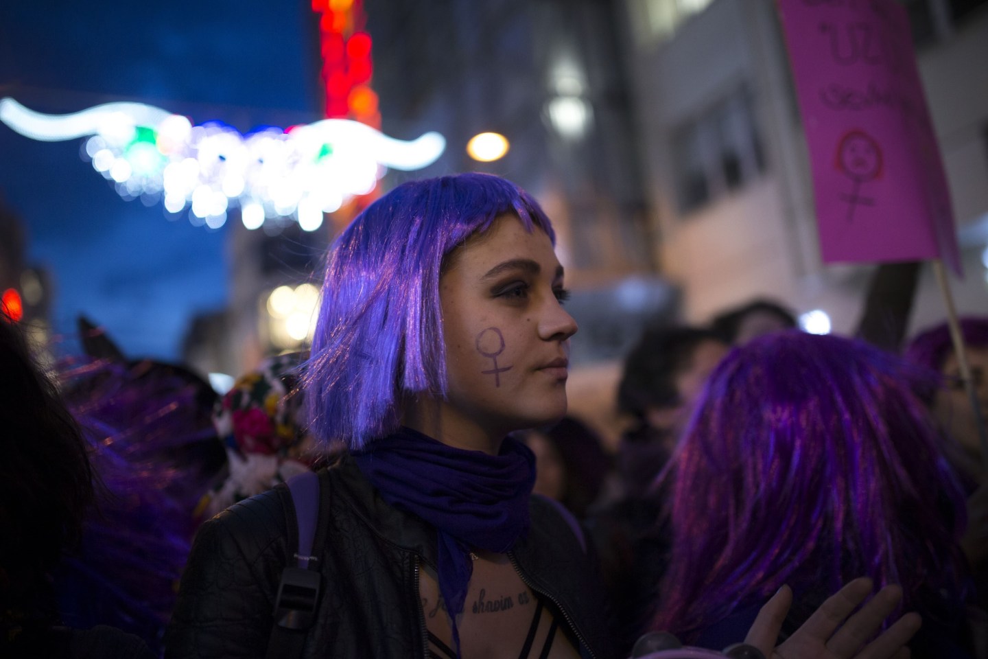 A woman in a purple wig takes part in an International Women's Day march.