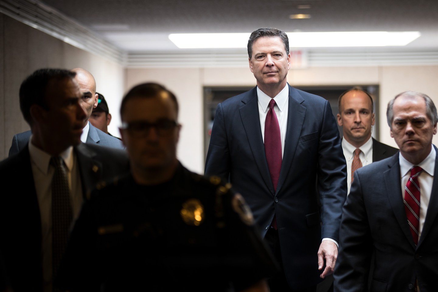 James Comey towers over other men as he walks down a hallway