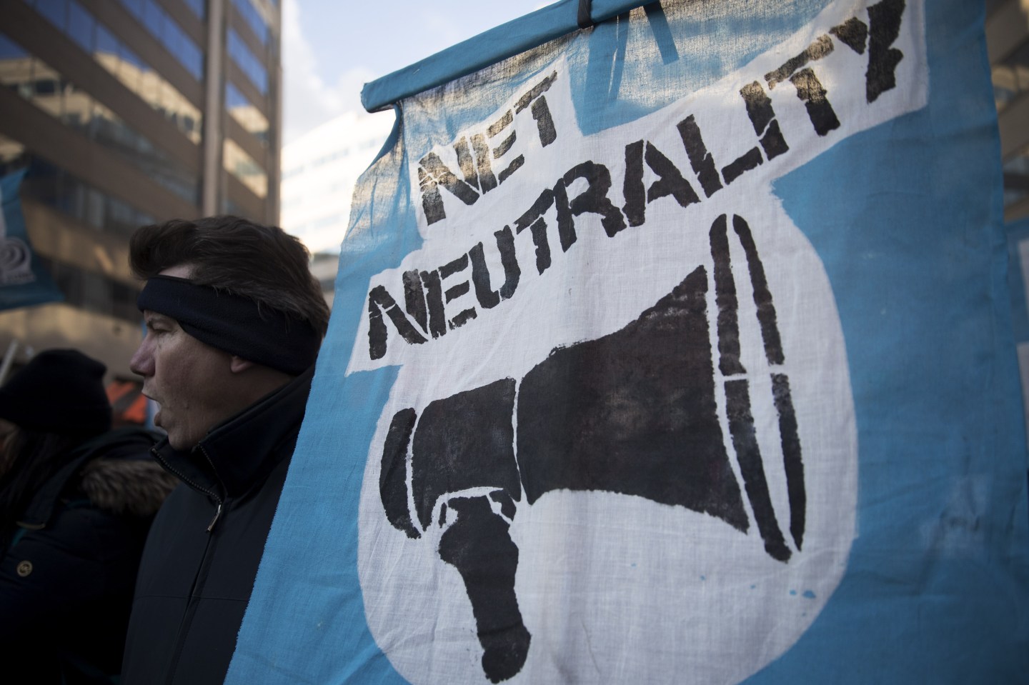 A protester opposed to FCC's rollback of net neutrality rules holds sign outside FCC headquarters.