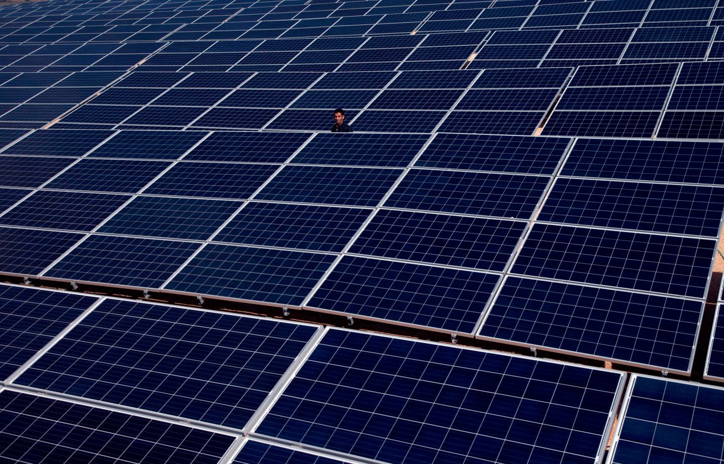 A man stand among rows of solar power panels