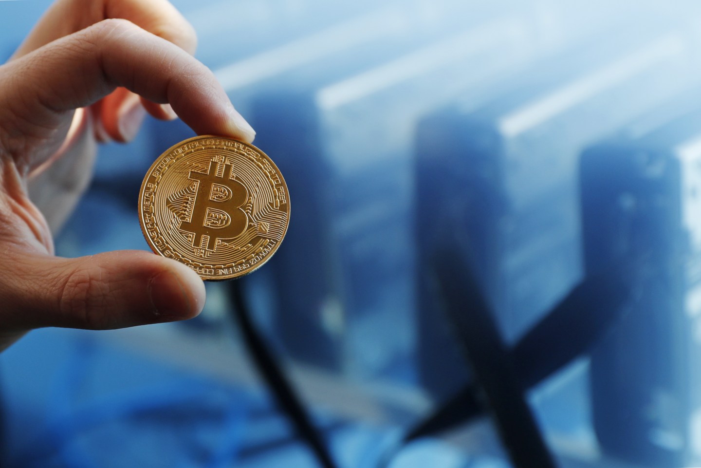 Human hand holds a physical representation of a Bitcoin.