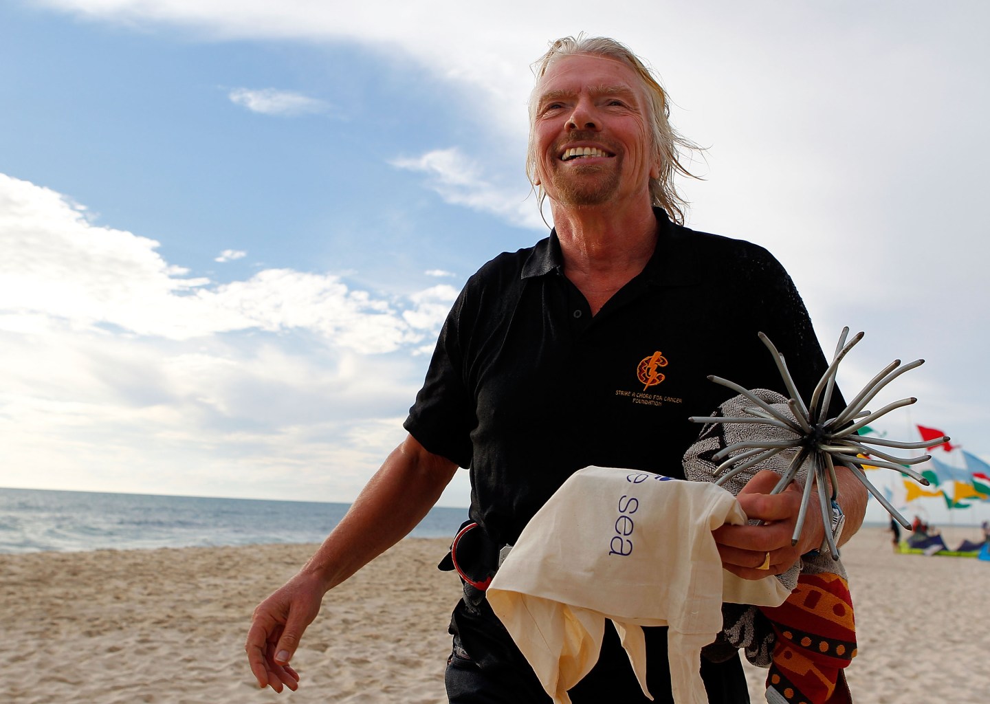 Richard Branson, Virgin founder, walks on a white sand beach.