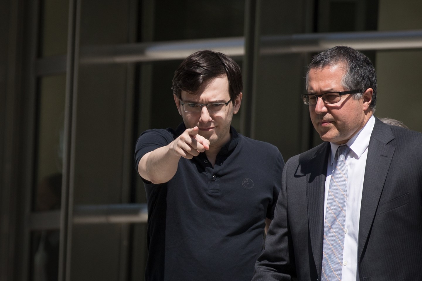Martin Shkreli points at the camera while walking out of court