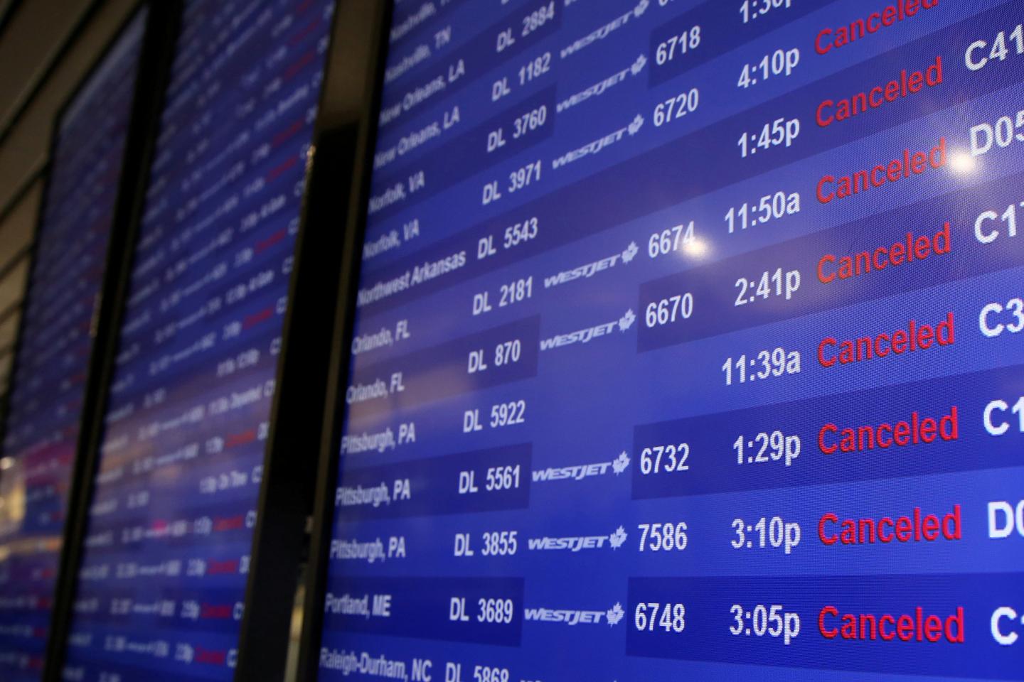 A flight monitor shows cancelled flights at LaGuardia Airport in New York