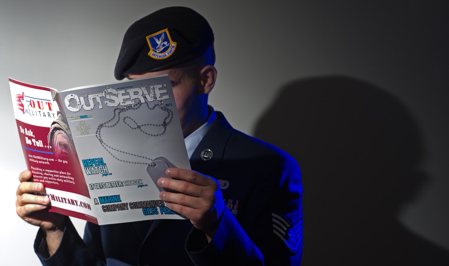A member of the U.S. military reads OutServe Magazine, raising the publication in front of their face.