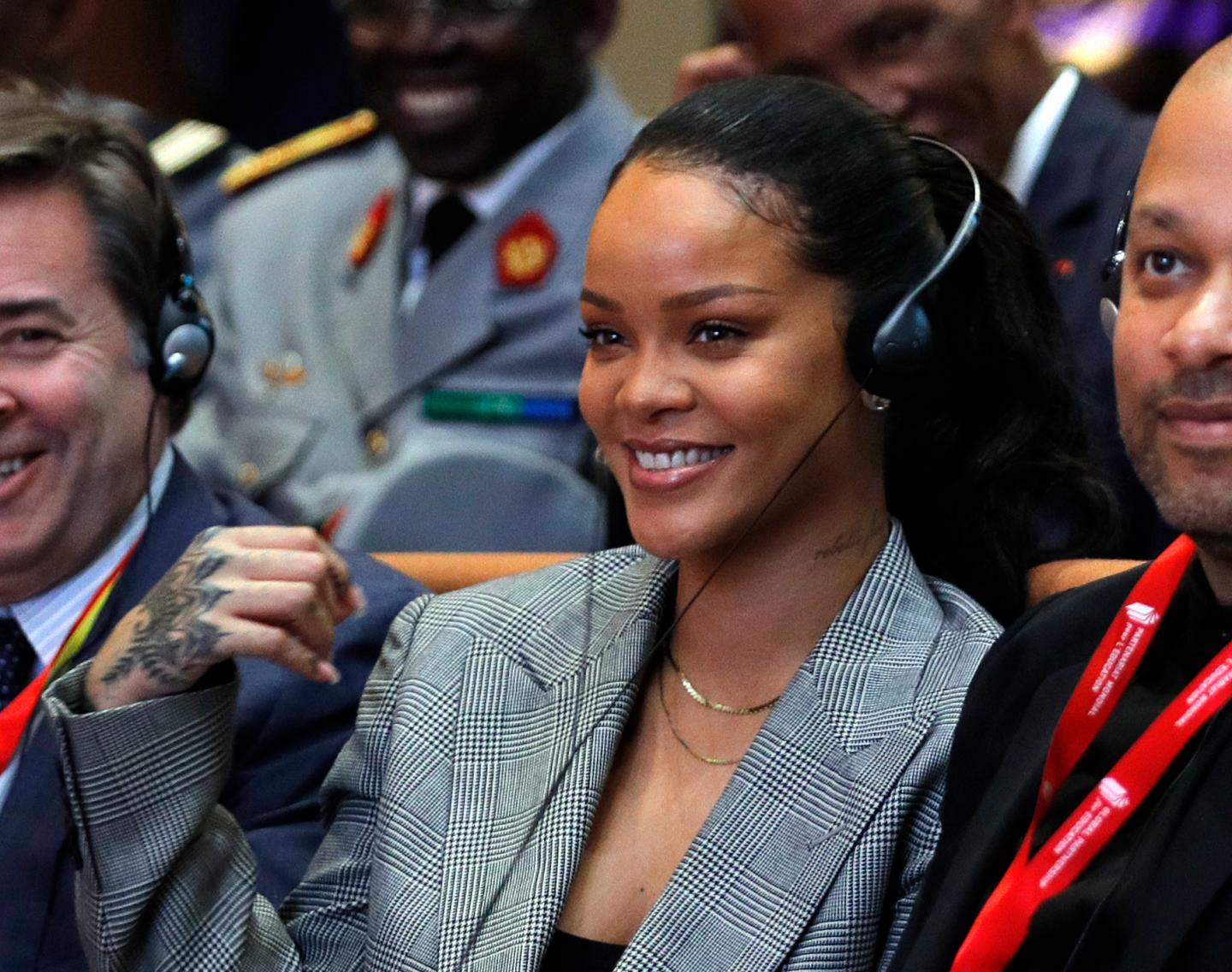 Rihanna wears headphones and smiles during a conference in France