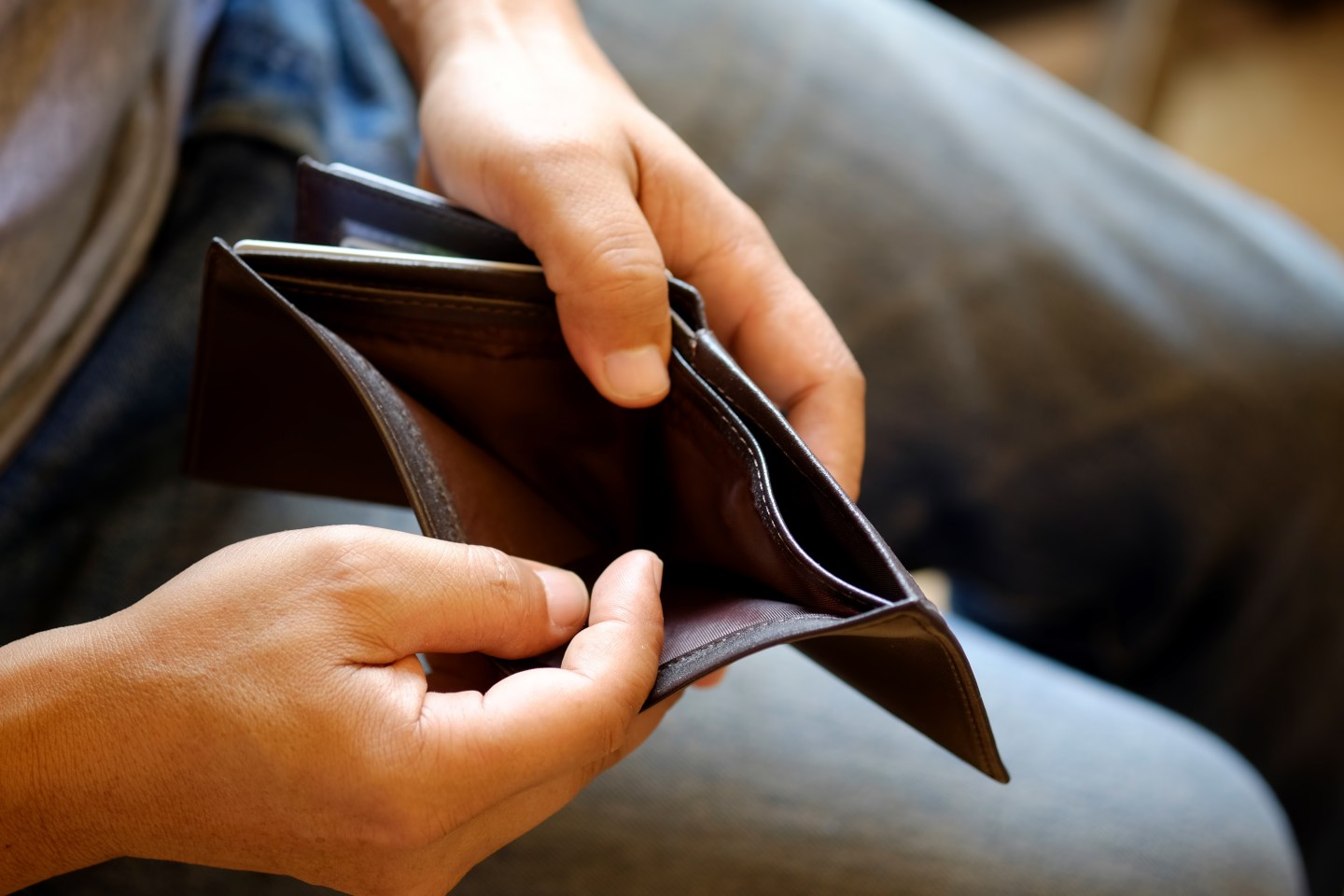Man looking at his empty leather wallet in office.