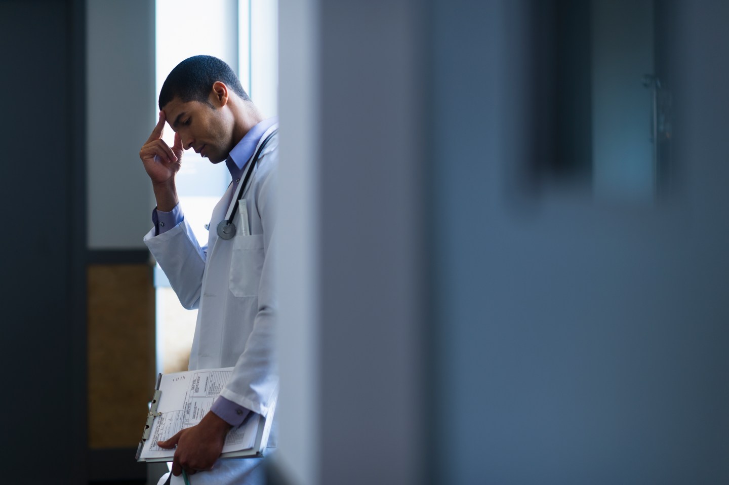 A male doctor looks down in frustration.