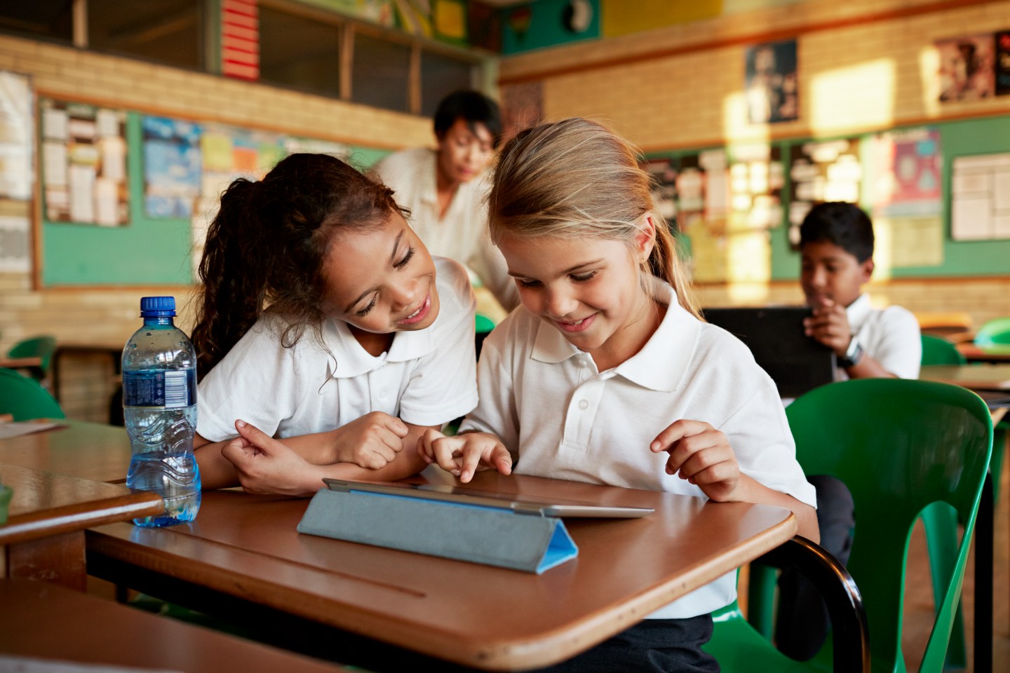 Schoolgirls looking at tablet togther and smiling