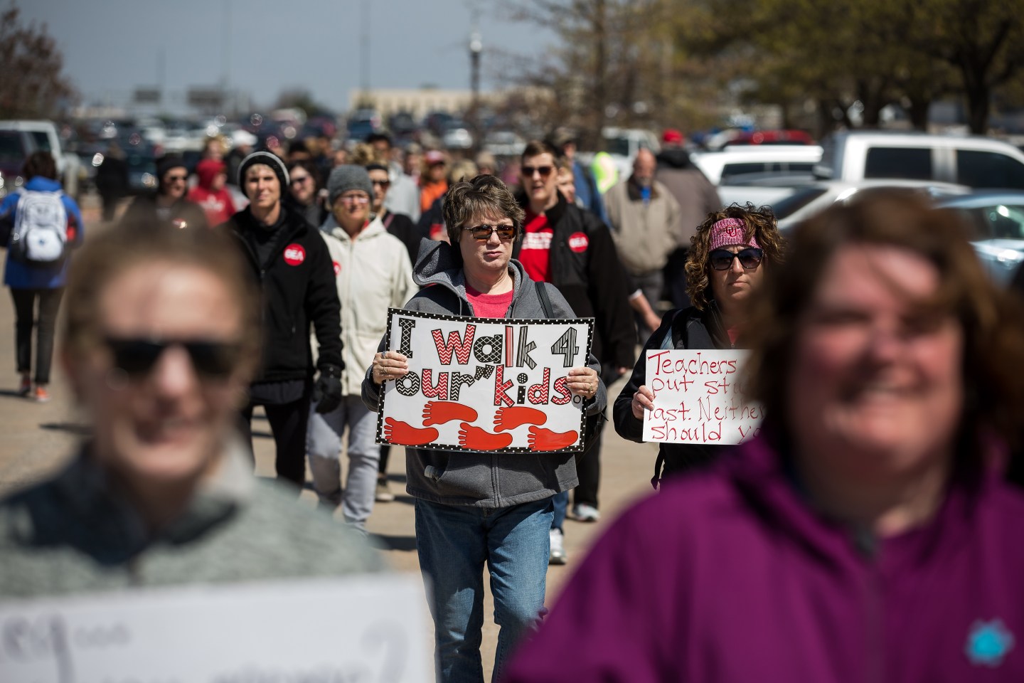 Woman holds 'I walk 4 our kids' sign as she participates in Oklahoma teacher strike.