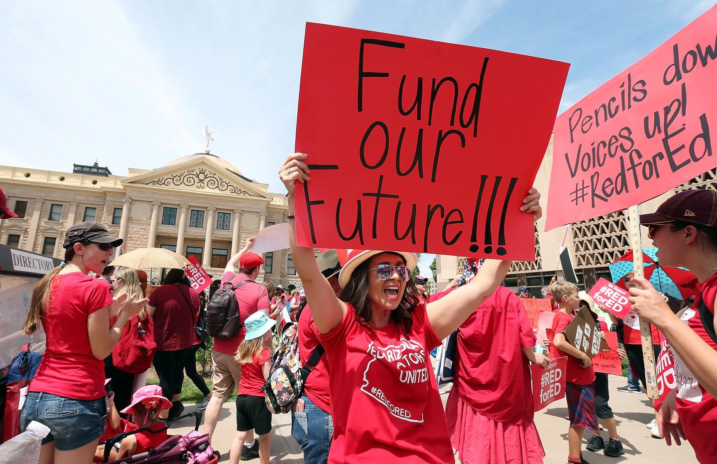 An Arizona teacher holds up a sign in front of the State Capitol during a rally on April 26, 2018 in Phoenix, Arizona.