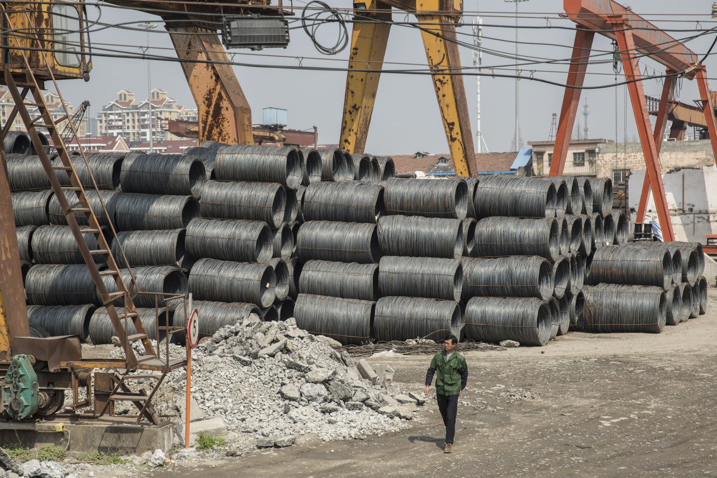 A worker walks past coils of steel wire at a depot on the outskirts of Shanghai, China.