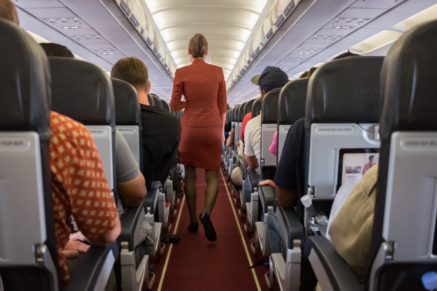 Female cabin crew walks away down aircraft cabin isle