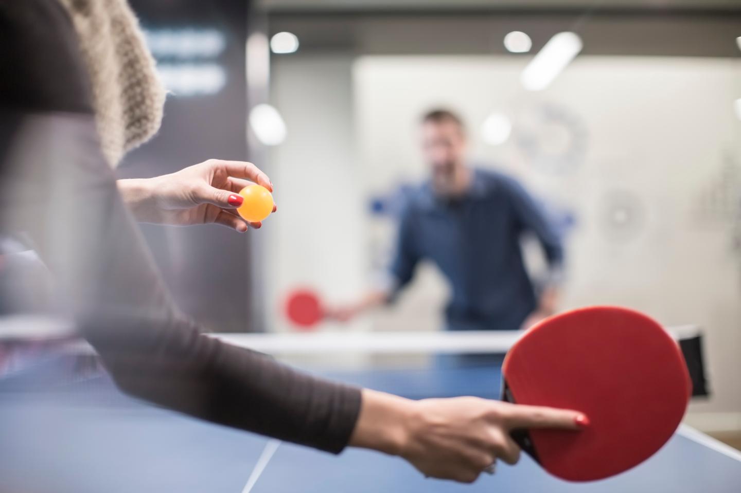 Two colleagues playing table tennis in office break room