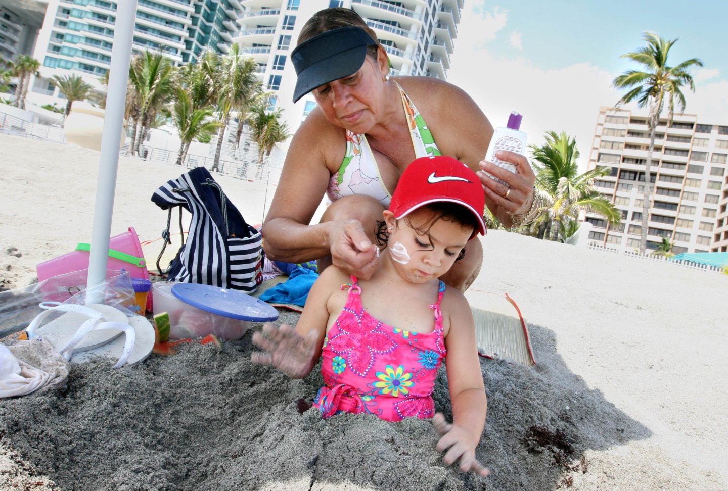 Vera Casanova, rear, applies sunscreen on her daughter Julie