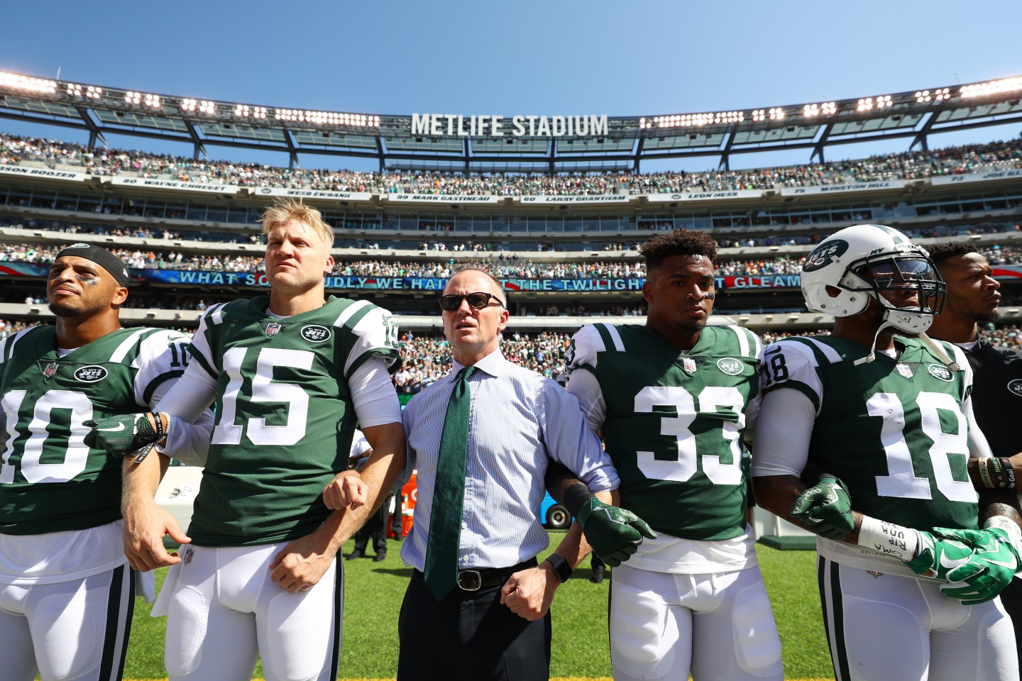Christopher Johnson, CEO of the New York Jets, stands in unison with his team during the National Anthem prior to an NFL game