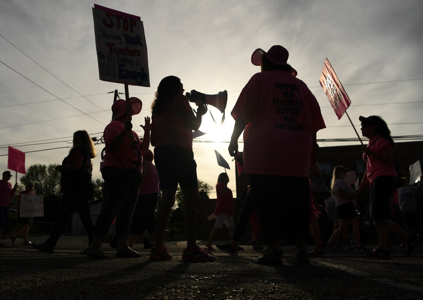 Teachers hold signs and a megaphone as they strike for higher wages in Colorado