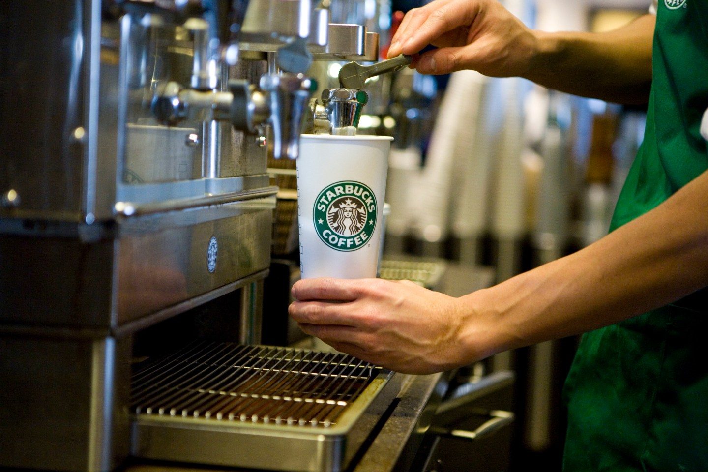 A Starbucks barista pours coffee into a branded cup