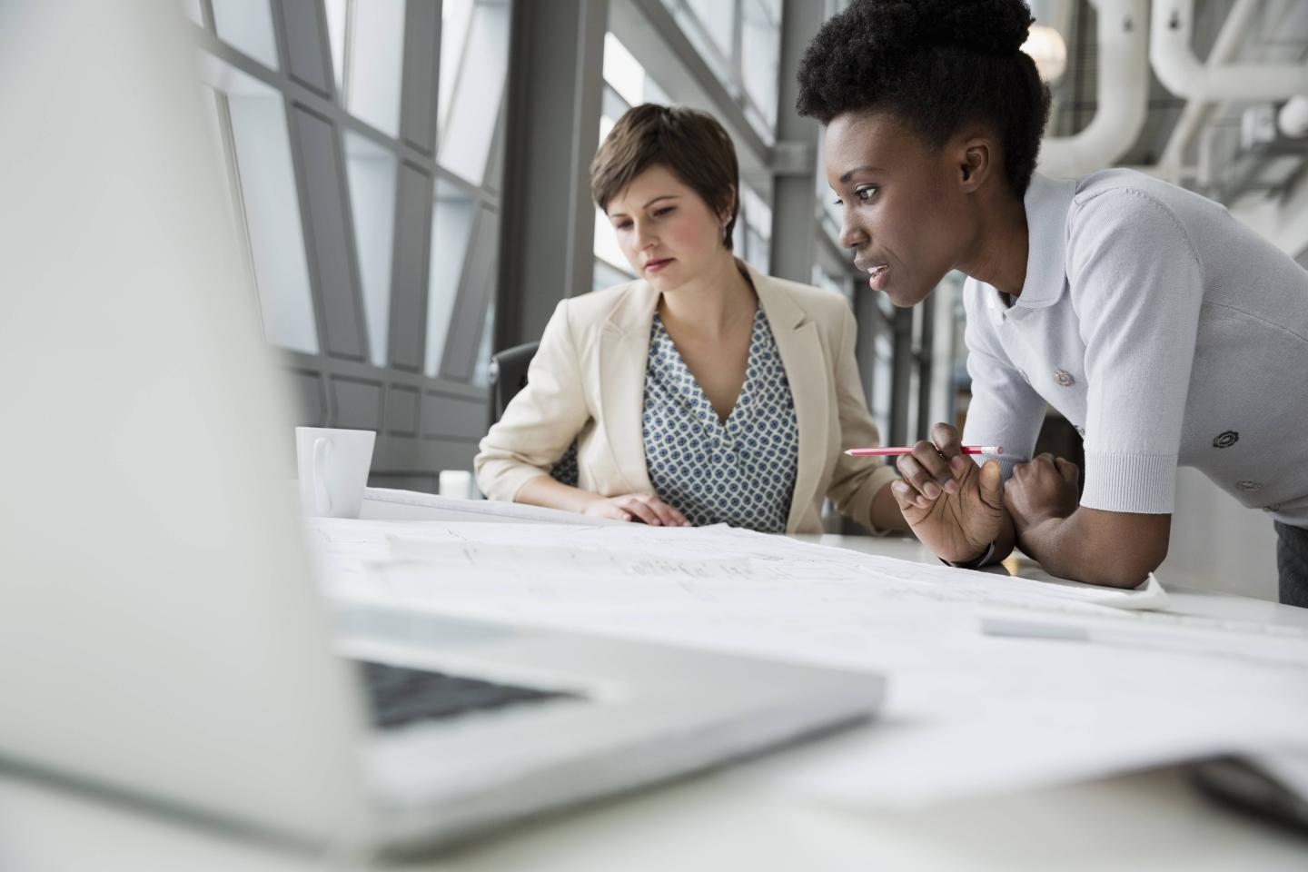Businesswomen looking at blueprint in office building