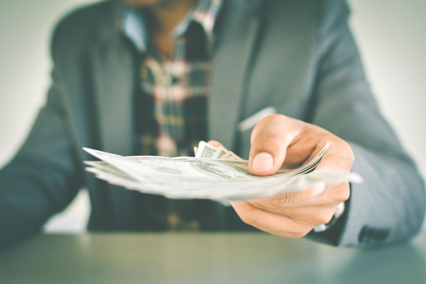 Midsection Of Businessman Holding Paper Currency At Table