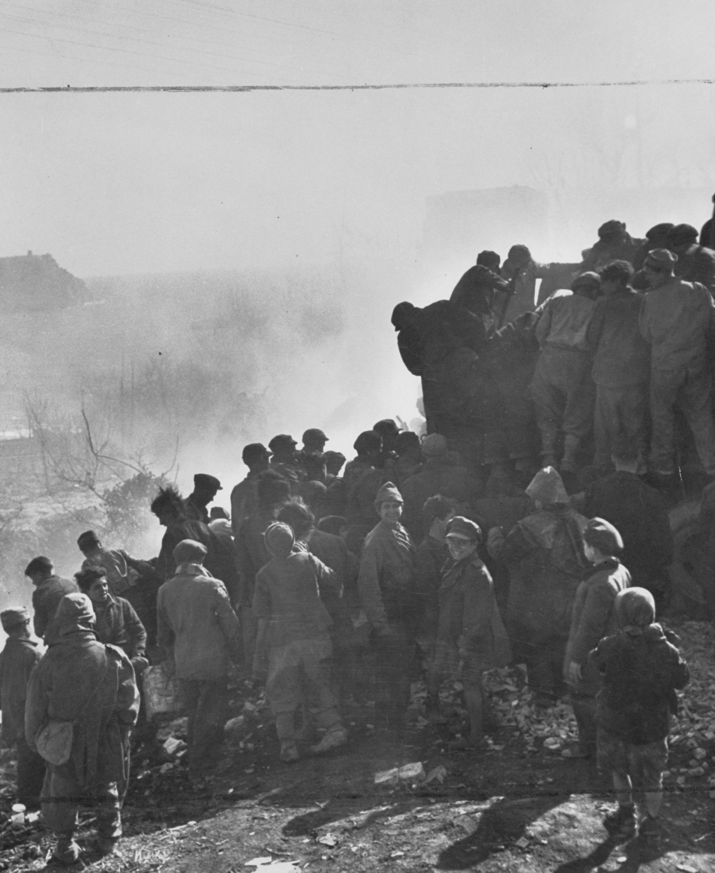 Italian children living in postwar conditions pick over refuse dumped from garbage trucks.