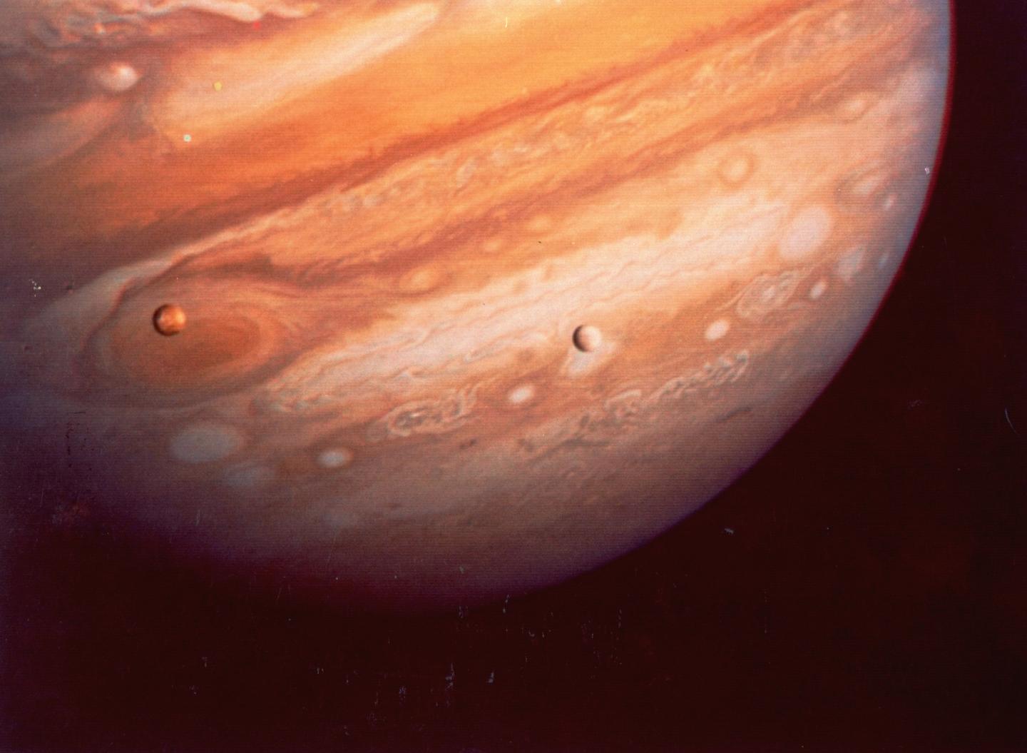 A portion of planet Jupiter and its moon