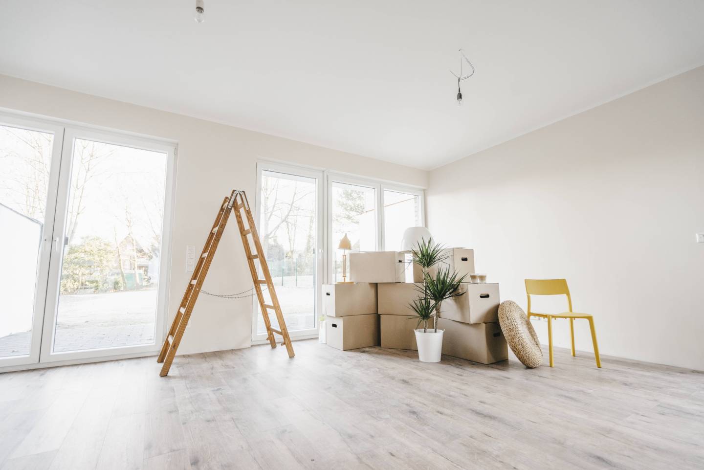 Moving boxes and ladder in empty room of a new home