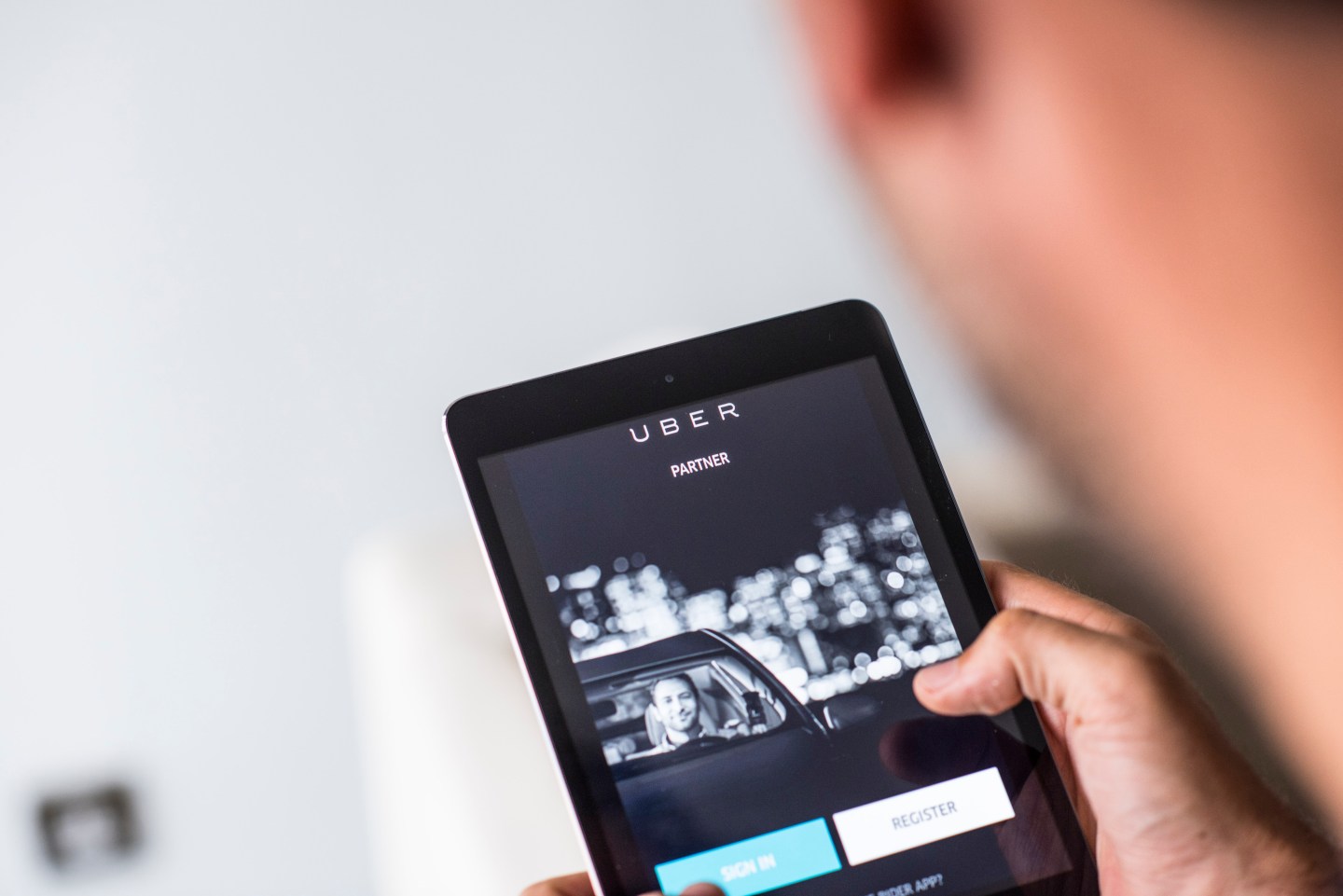 Young man holds a smart device while using Uber app