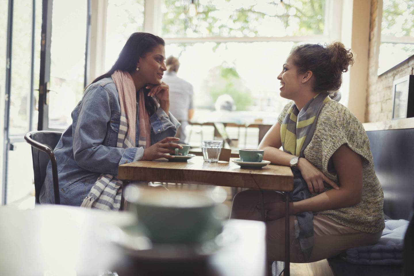 Women friends drinking coffee and talking at cafe table