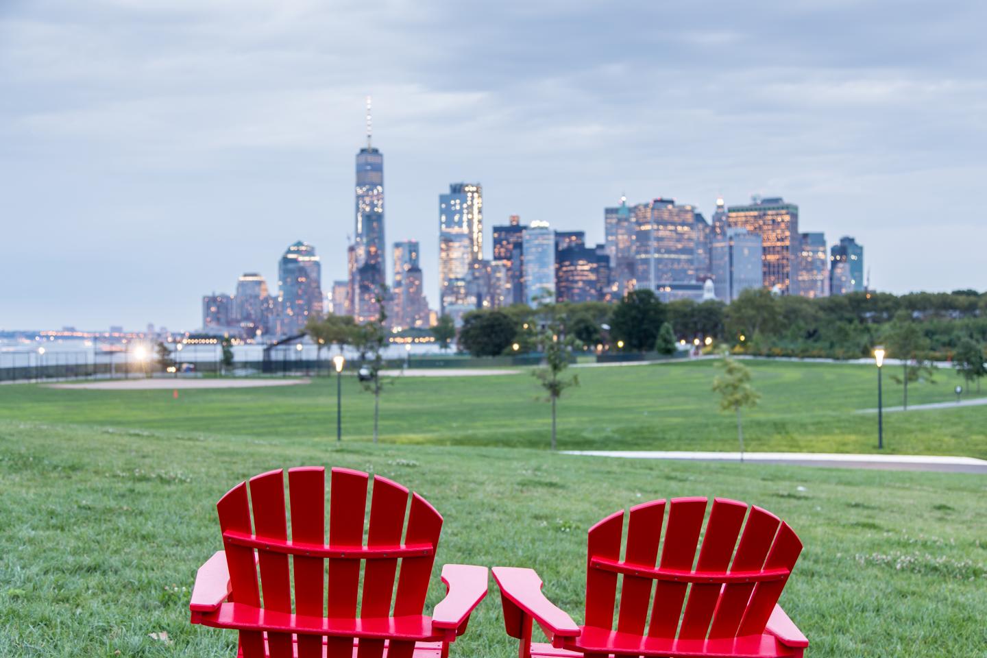 Red Adirondack chairs with a view of Downtown Manhattan