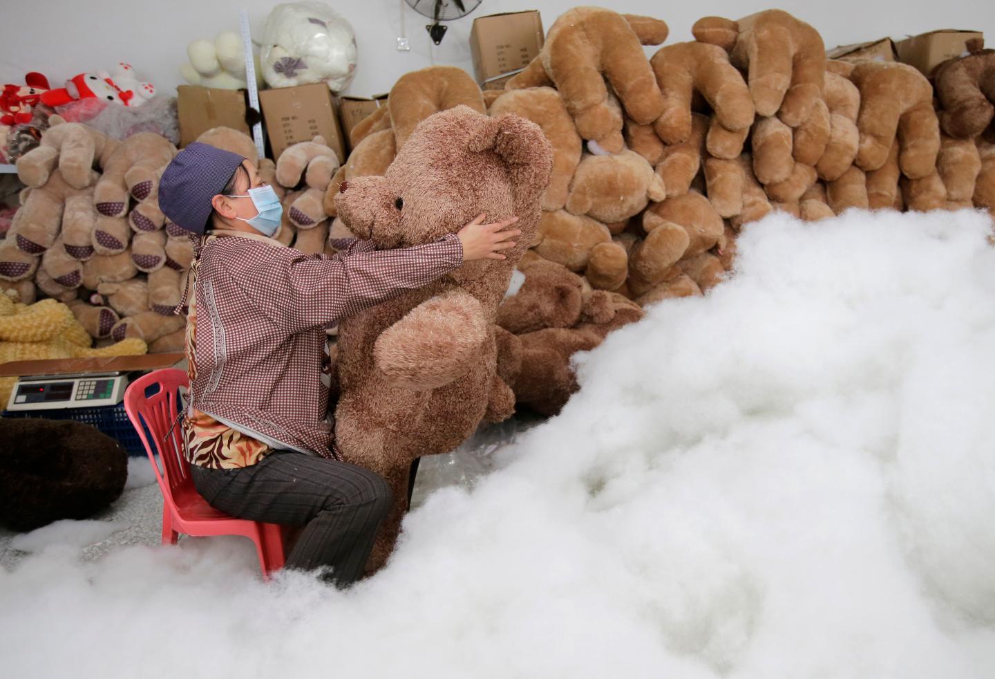 A worker stuffs a toy bear with cotton at a toy factory in Wuhan