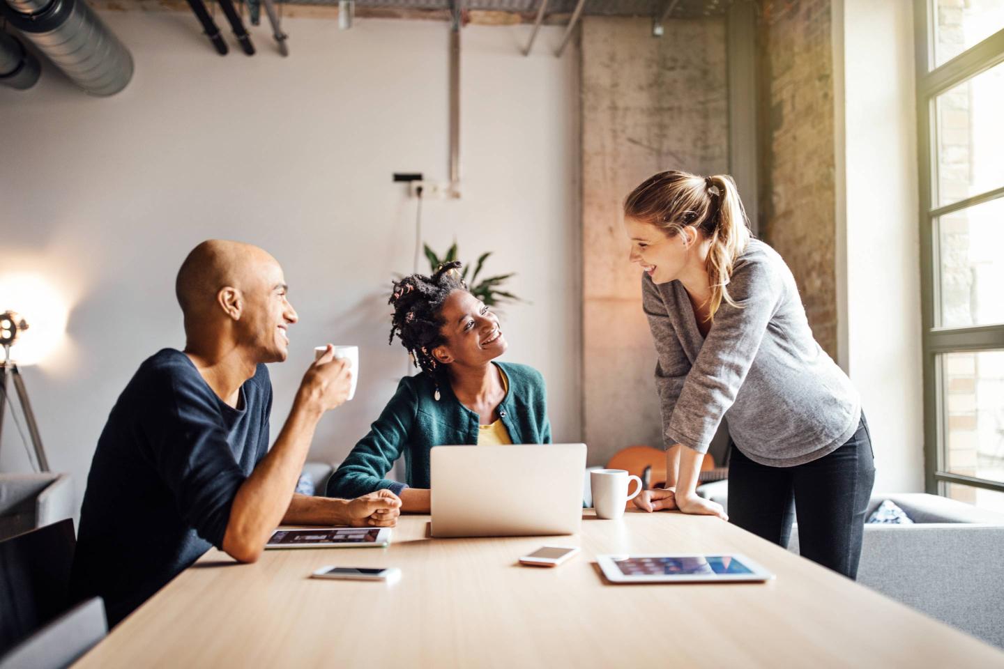 Business colleagues talking while using laptop at office