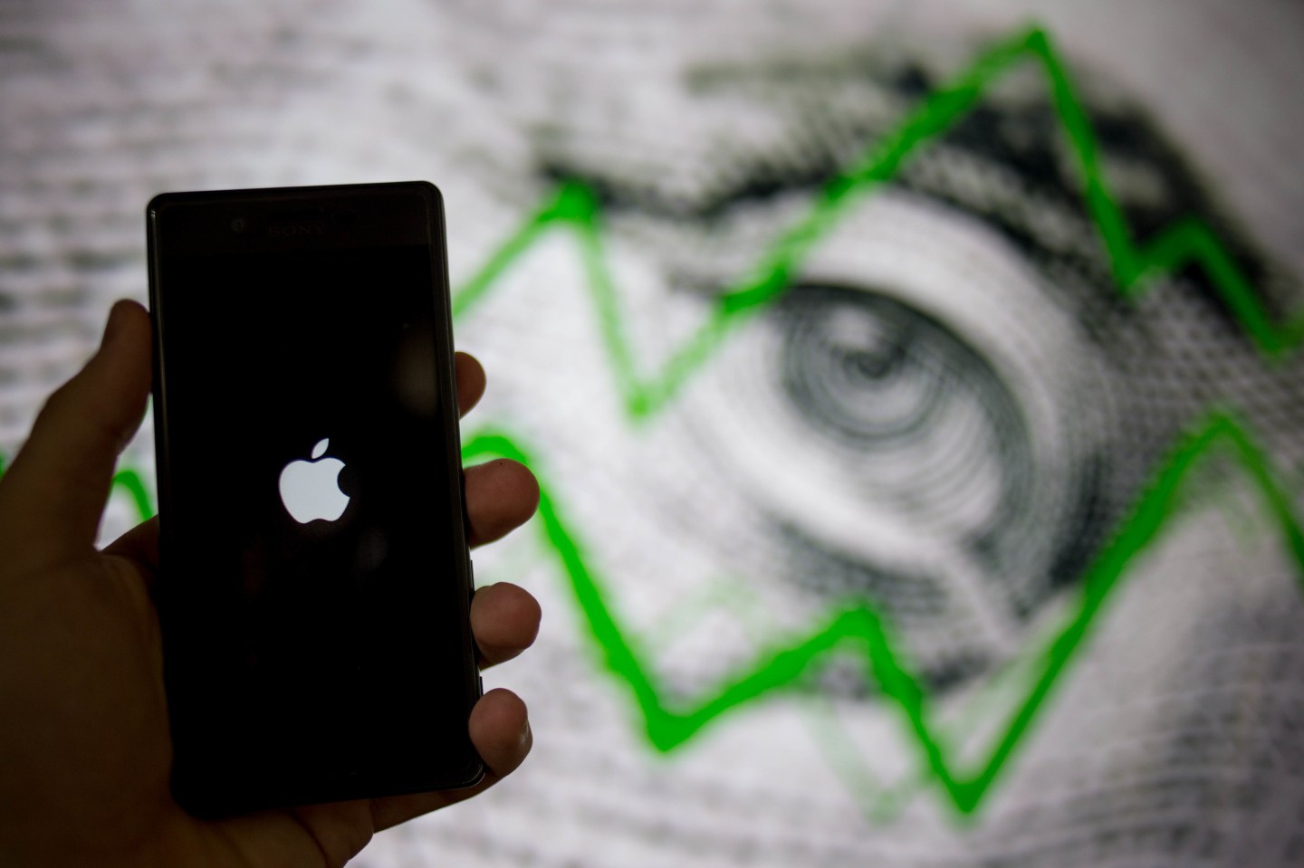 The Apple logo seen on a cellphone with a background of a