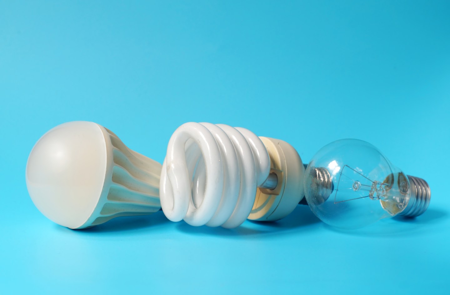 Led lamp, fluorescent lamp and incandescent lamp on blue background