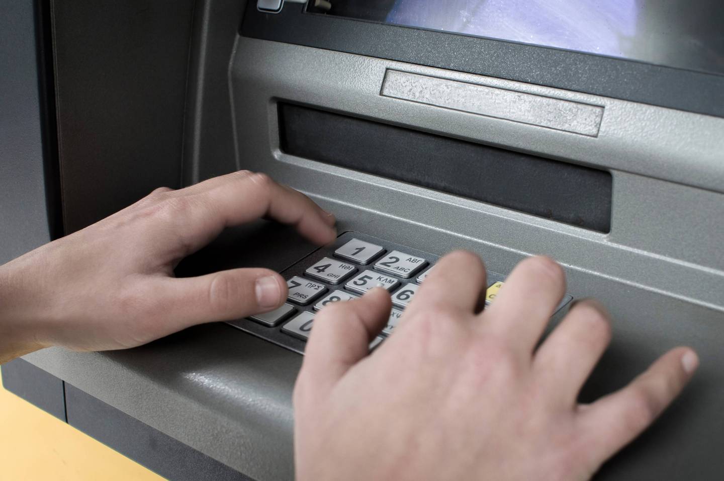 A woman seen typing in the pin on an ATM.People withdrawing