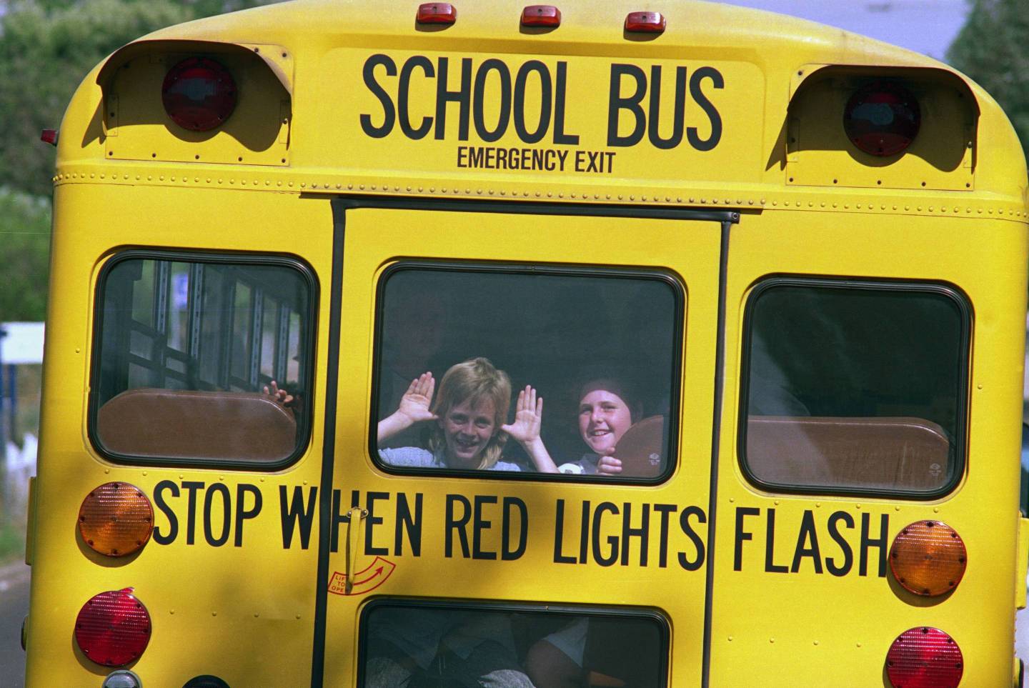 Children Waving from Back of School Bus