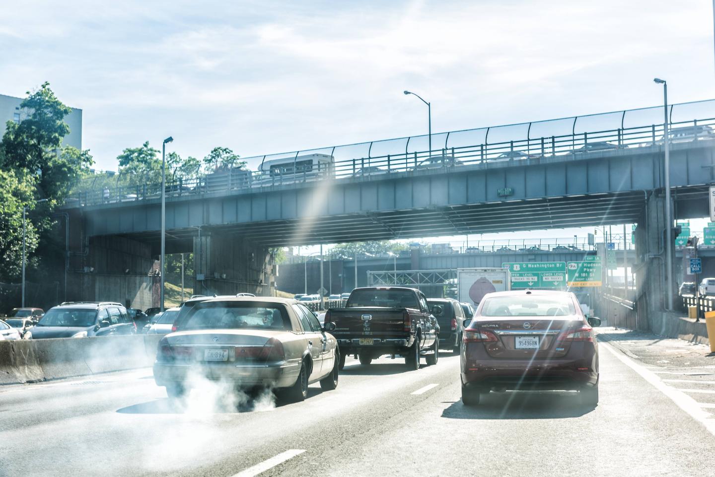 Road and street highway in NYC with sign for George Washington Bridge, smoke coming out of exhaust pipe of car